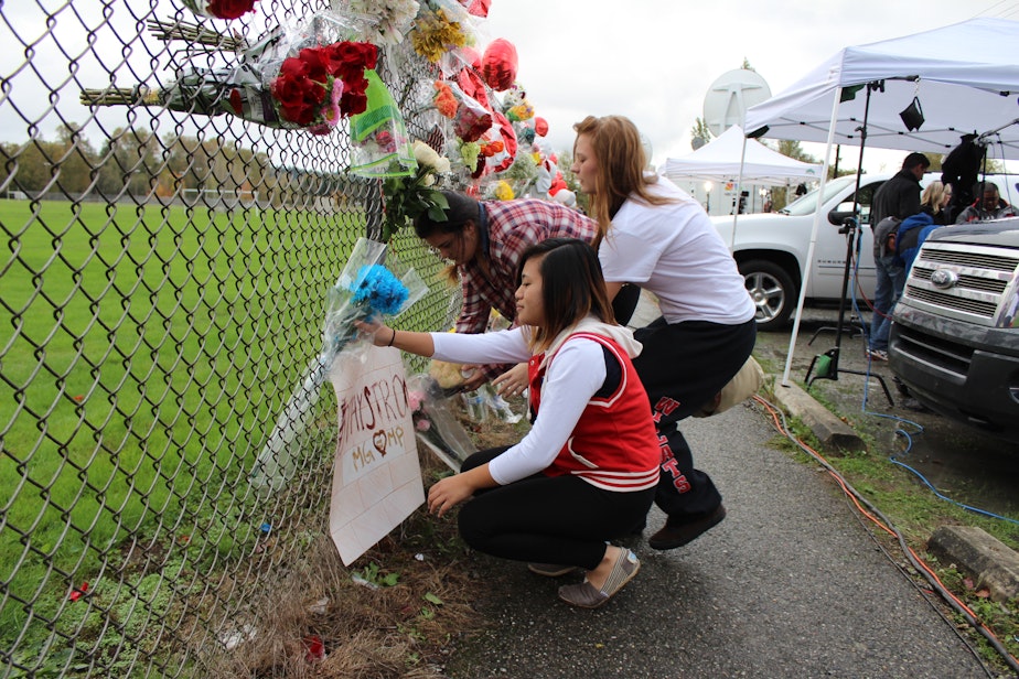 caption: Students put flowers on a memorial for the shooting victims at Marysville-Pilchuck High School in October 2014.