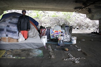 caption: Some residents of the Jungle kept tidy encampments, like William Kowang above, while others lived in garbage with needles strewn about.