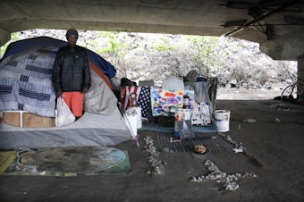 caption: Some residents of the Jungle kept tidy encampments, like William Kowang above, while others lived in garbage with needles strewn about.