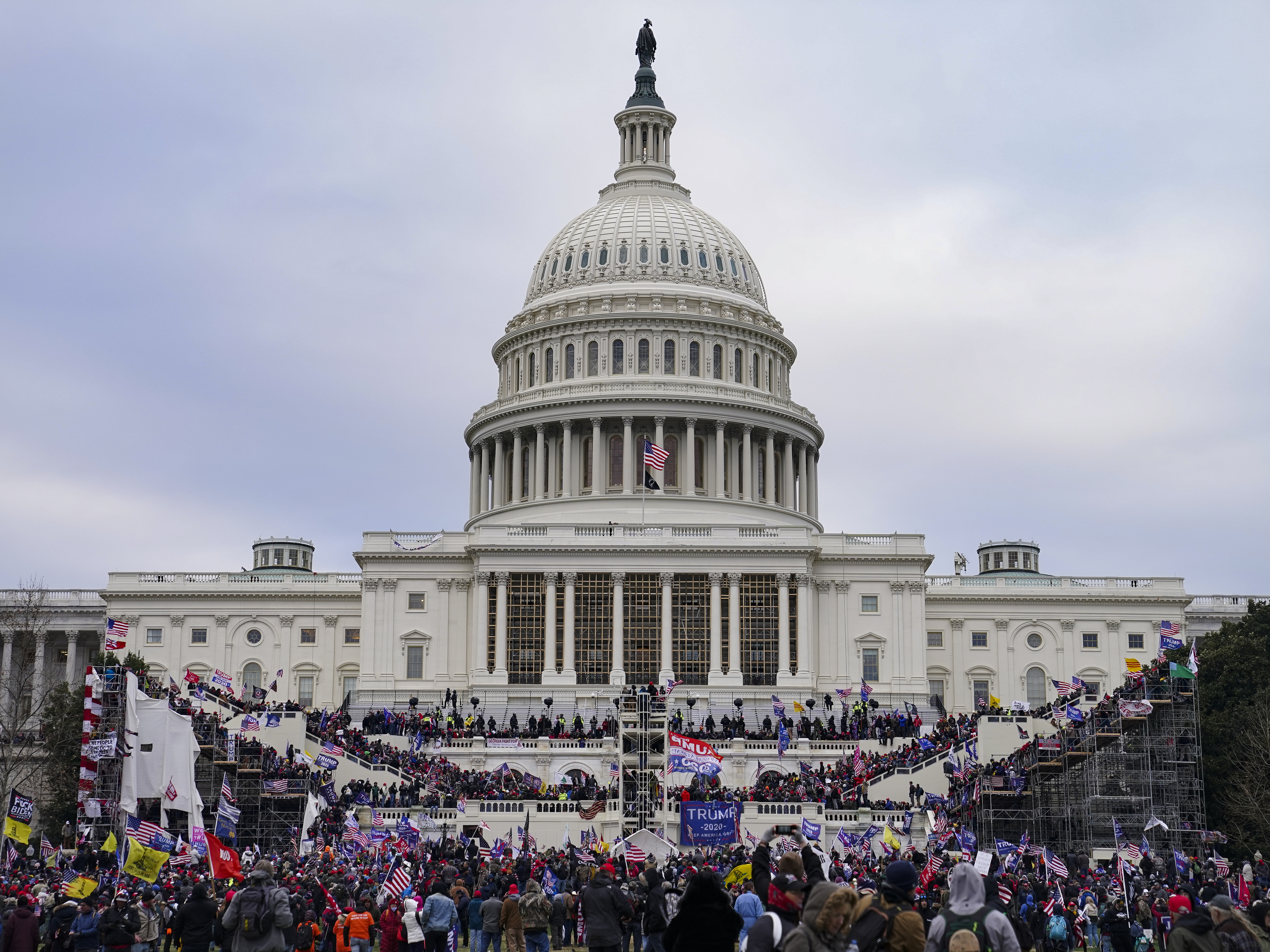 caption: Protesters storm the Capitol on Jan. 6. Three individuals associated with an extremist group were indicted Wednesday on charges that include conspiracy and obstructing an official proceeding.