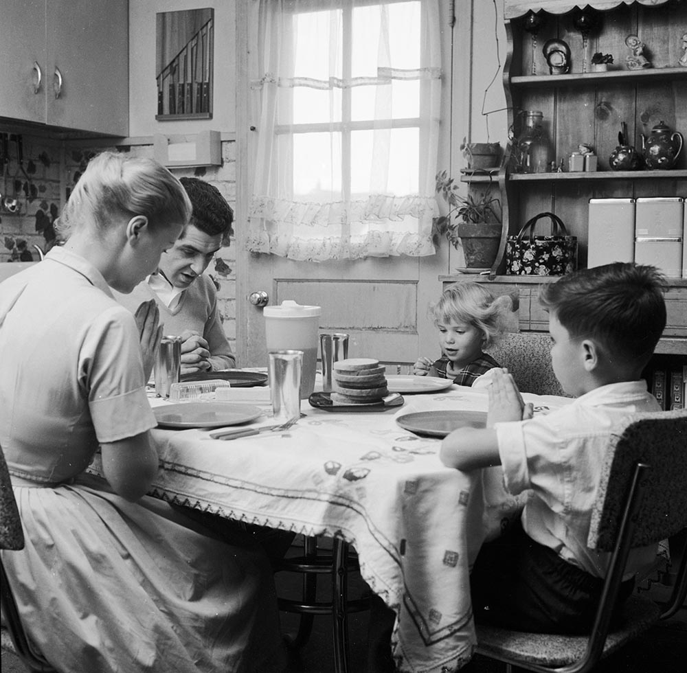 caption: Mr. and Mrs. Paul, and their children Belinda and Cliff, say grace before starting their meal.  (Jacobsen /Three Lions/Getty Images)