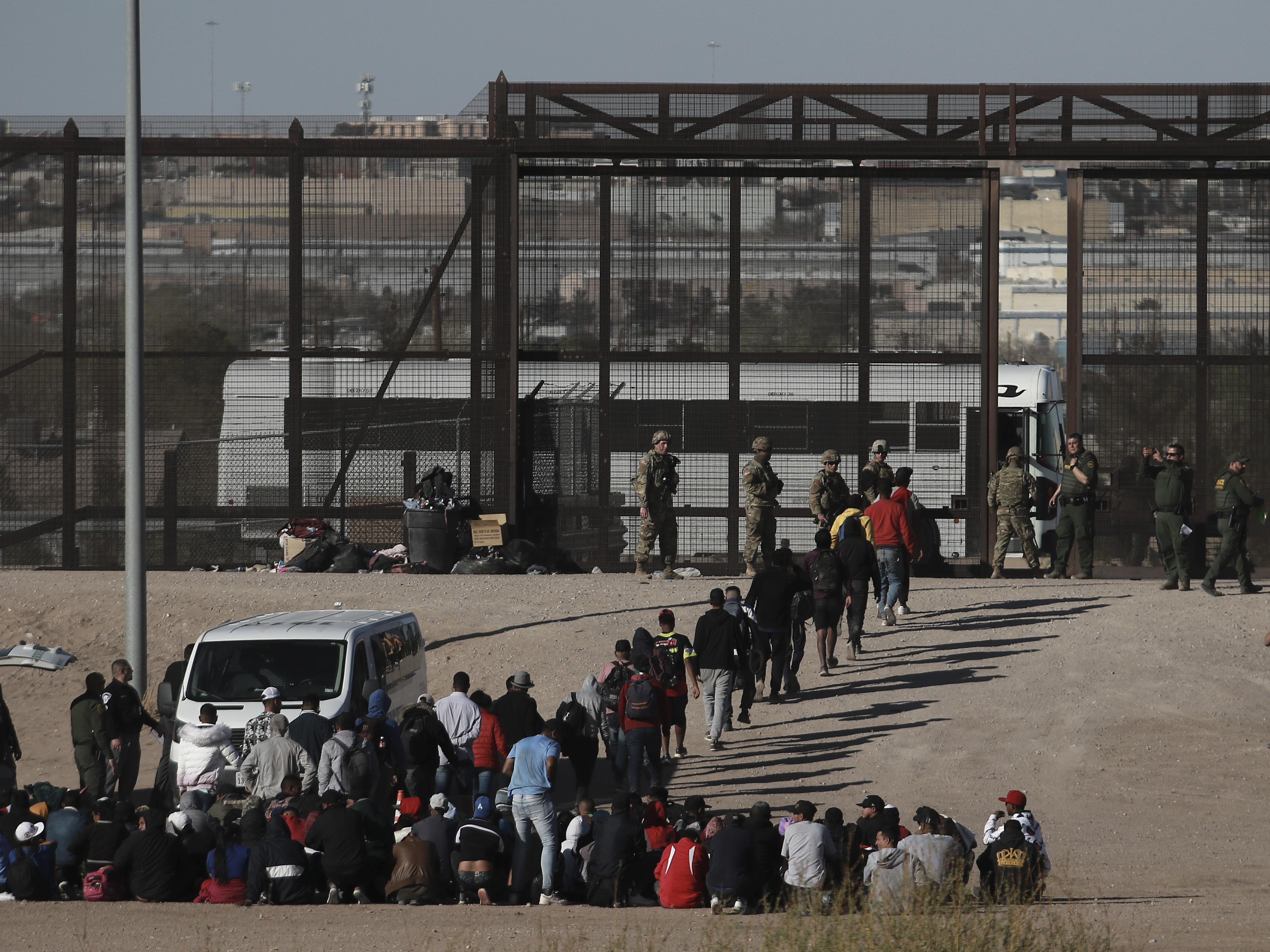 caption: Migrants walk into U.S. custody after crossing the border from Mexico, Ciudad Juarez, Wednesday, March 29, 2023.