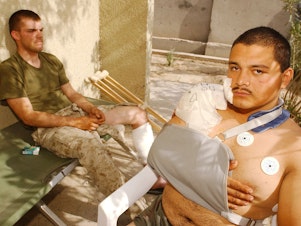 caption: U.S. Marine Corps Lance Cpls. Chris Covington (left) and Carlos Gomez Perez recover from shrapnel and bullet wounds on April 27, 2004, after Iraqi insurgents attacked near Fallujah, Iraq. Just two weeks earlier, Covington and Gomez Perez helped evacuate wounded Marines and soldiers after a deadly explosion rocked a schoolhouse in Fallujah.