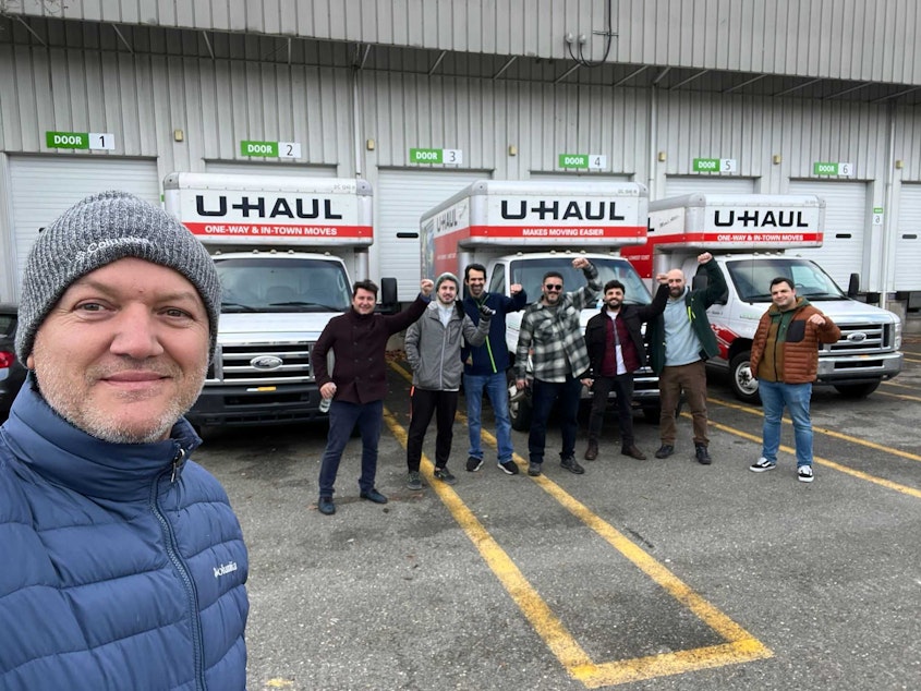 caption: Tufan Erdinc, president of the Turkish American Cultural Association of Washington State and other members of the group, stand in front of trucks full of care packages headed for Turkey. 