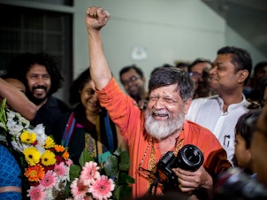 caption: Bangladeshi photographer and activist Shahidul Alam, center, reacts as he is released from Dhaka Central Jail, Keraniganj, near Dhaka on Tuesday.