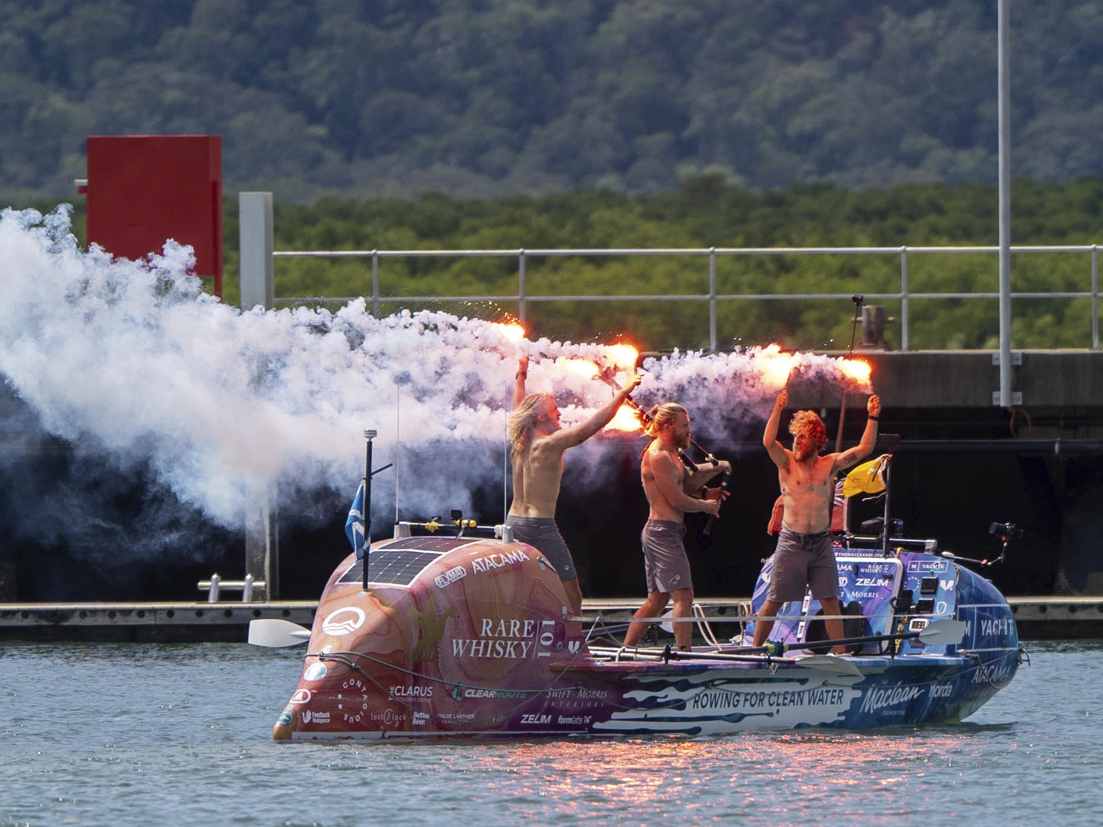 caption: Scottish brothers, Ewan, Jamie and Lachlan, Maclean react after completing their record-breaking row from Peru across the Pacific Ocean to Cairns, Australia, on Saturday