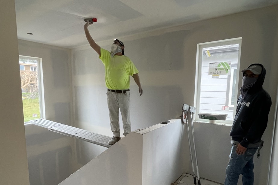 caption: A worker sands drywall seams at a single family home at the Braes park housing development in Edmonds.