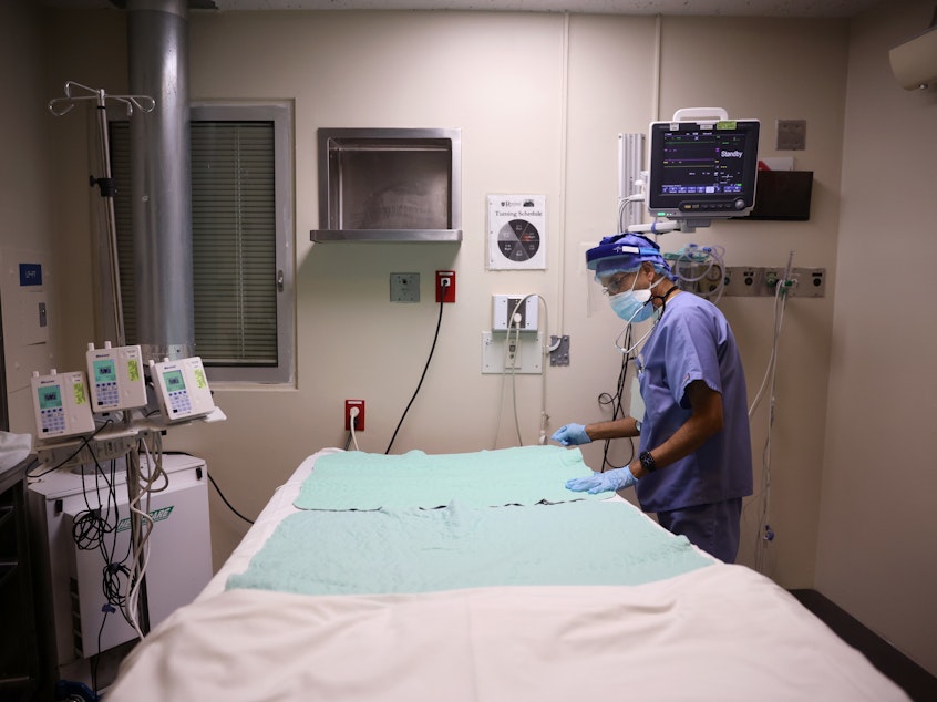caption: Intensive Care Unit nurse Subramanya Kirugulige prepares a bed for an arriving COVID-19 patient at Roseland Community Hospital in Chicago in December. A large study has found that people with severe initial cases of COVID-19 tend to be at greater risk of more health problems later on.