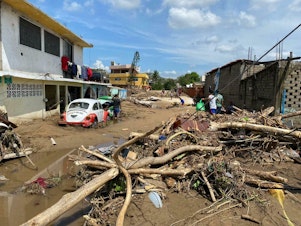 caption: A river carried mud and downed trees in the Zapata neighborhood on the outskirts of the city of Acapulco, Mexico, after Hurricane Otis swept through the area.