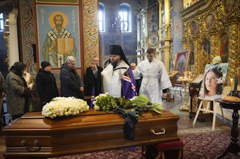 caption: A priest prays over the coffin of Oleksandra "Sasha" Kuvshynova, a Ukrainian journalist killed while working for Fox News in March 2022. Her parents have sued Fox News alleging wrongful death, fraud and defamation.