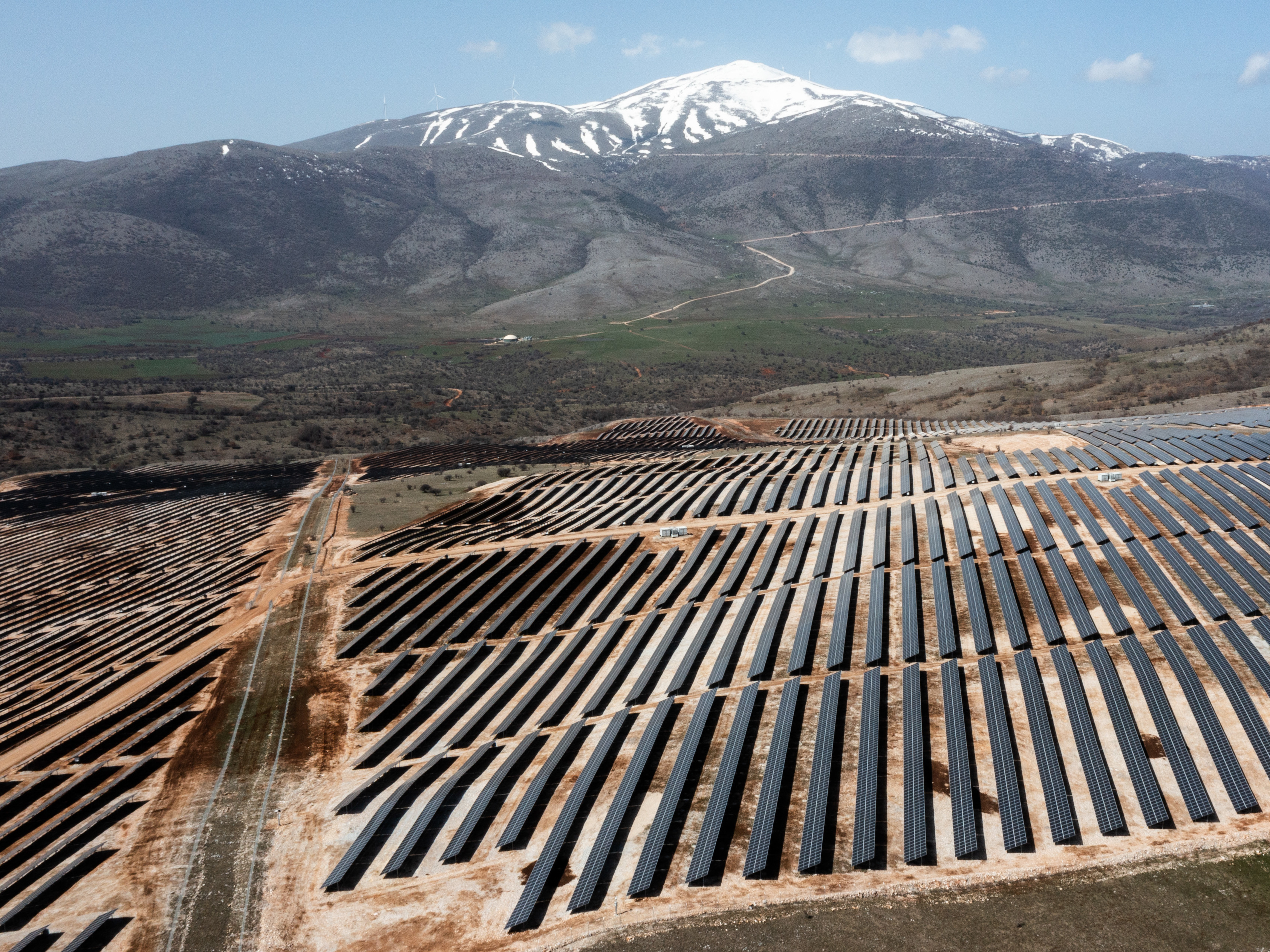 caption: An array of photovoltaic panels are pictured at a solar power park in Kozani, Greece on April 6, 2022. Greece's power transmission operator says it recently hit a new benchmark, using exclusively renewable energy for a brief time.