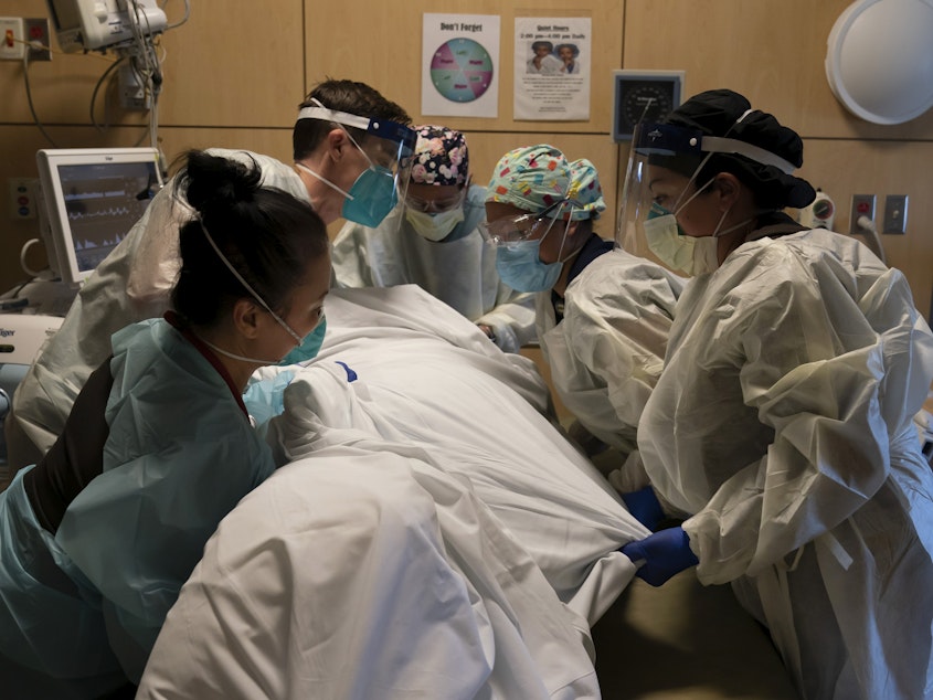 caption: Medical personnel treat a COVID-19 patient at Providence Holy Cross Medical Center in Los Angeles on Thursday. California is imposing an overnight curfew on most residents to blunt a surge in coronavirus infections.