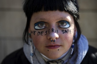 caption: E.O., a sophomore at Ingraham high school, is portrayed with the words ‘we deserve safety’ painted across their face during a student walkout in protest of gun violence in schools on Monday, November 14, 2022, at Seattle City Hall. 