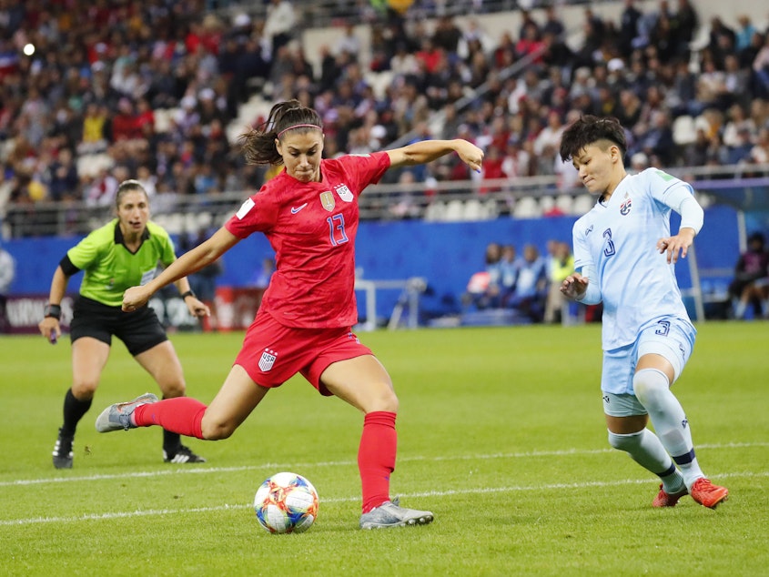 caption: U.S. forward Alex Morgan shoots and scores while defended by Thailand's Natthakarn Chinwong on Tuesday in Reims, France, in the group stage of the Women's World Cup.
