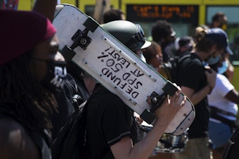 caption: A protester's skateboard reads 'Defund SPD 50% at least!' during the Defund The Police march and rally from the King County Juvenile Detention Center to Seattle City Hall on Wednesday August 5, 2020, in Seattle.