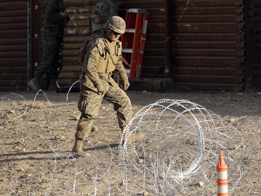 caption: A Marine uses concertina wire to fortify the border separating Tijuana, Mexico, and San Diego, near the San Ysidro Port of Entry.