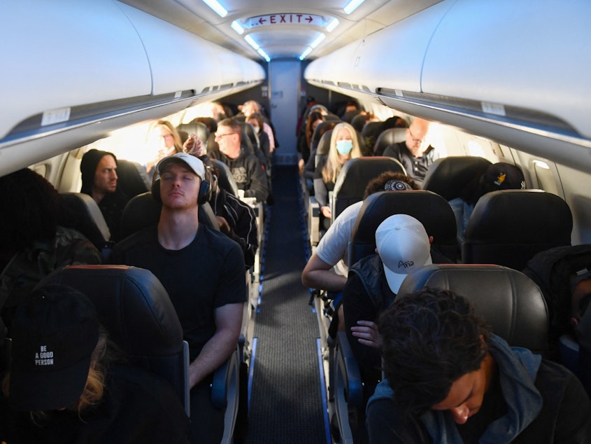 caption: Airline passengers, some not wearing face masks following the end of the federal mask mandate, sit during a American Airlines flight operated by SkyWest Airlines from Los Angeles International Airport to Denver, on Tuesday.