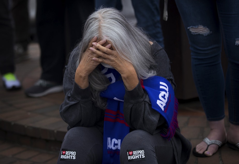 caption: Jackie Jacobs holds her head in her hands before the start of a pro-choice rally and press conference on Tuesday, May 3, 2022, at Kerry Park in Seattle. 