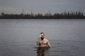 caption: Nikolai Pastuchenko crosses himself as he takes a dip into the Dnipro River in Dnipro, Ukraine, on Thursday.