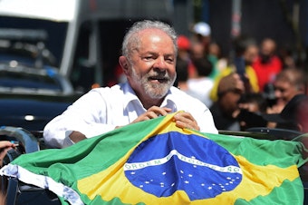 caption: Luiz Inacio Lula da Silva holds a Brazilian flag while leaving a polling station in Sao Paolo during Sunday's presidential runoff election.