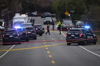 caption: Police investigate the scene of a fatal carjacking and shooting on Wednesday, March 27, 2019, at the intersection of 120th Street and Sandpoint Way Northeast in Seattle. 