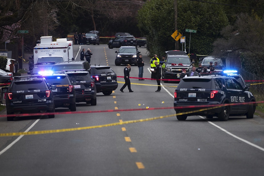 caption: Police investigate the scene of a fatal carjacking and shooting on Wednesday, March 27, 2019, at the intersection of 120th Street and Sandpoint Way Northeast in Seattle. 