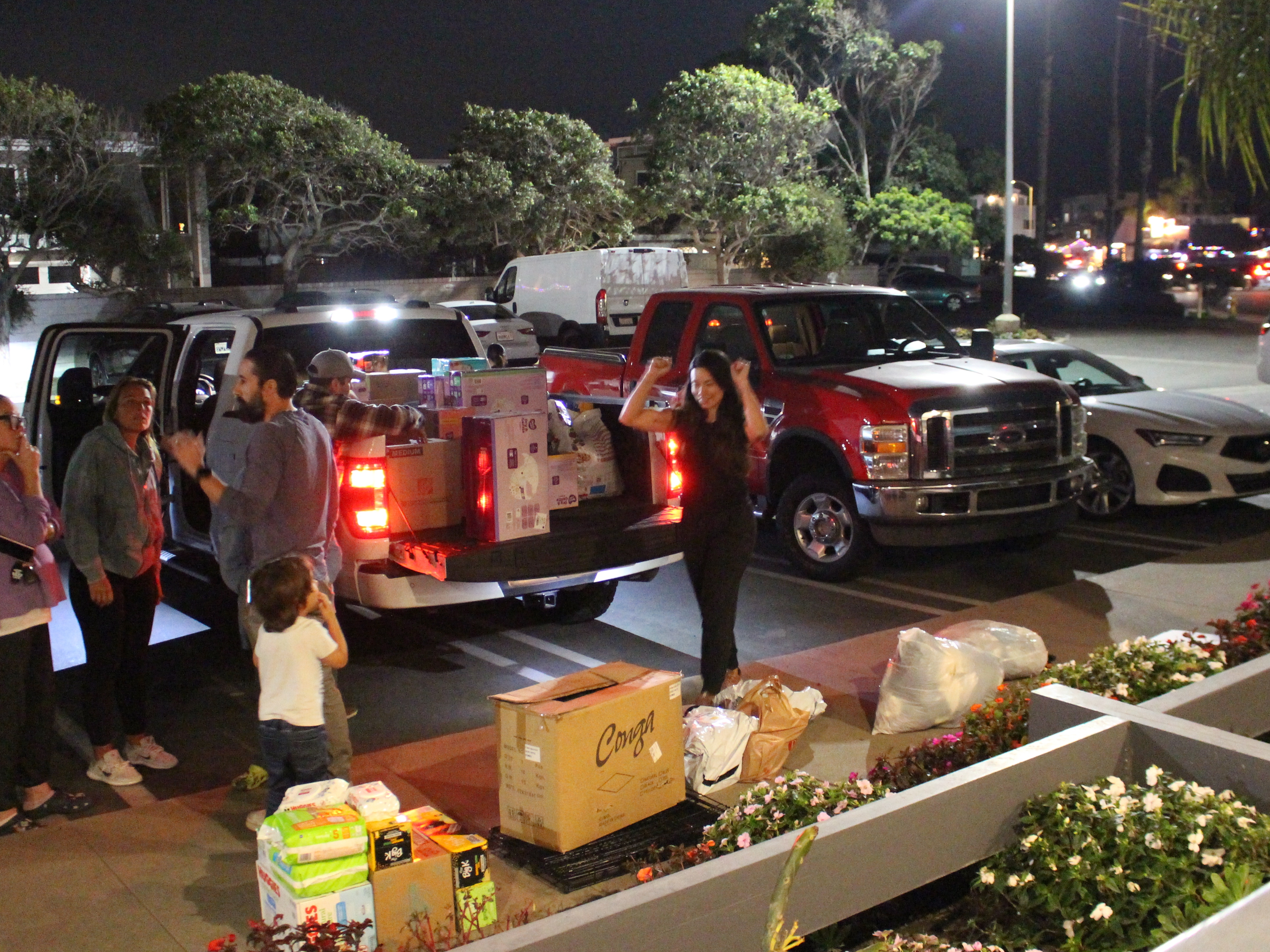 caption: Lauren Gruel, pictured at right, celebrates having filled another truck bed with community-donated supplies on Thursday. She and her husband Andrew turned their Huntington Beach restaurant into a donation hub to support wildfire victims in Los Angeles.