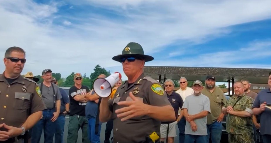 caption: In this screenshot from a YouTube video, Lewis County Sheriff Robert Snaza tells a crowd "Don't be a sheep" when it comes to following Gov. Jay Inslee's face covering order.