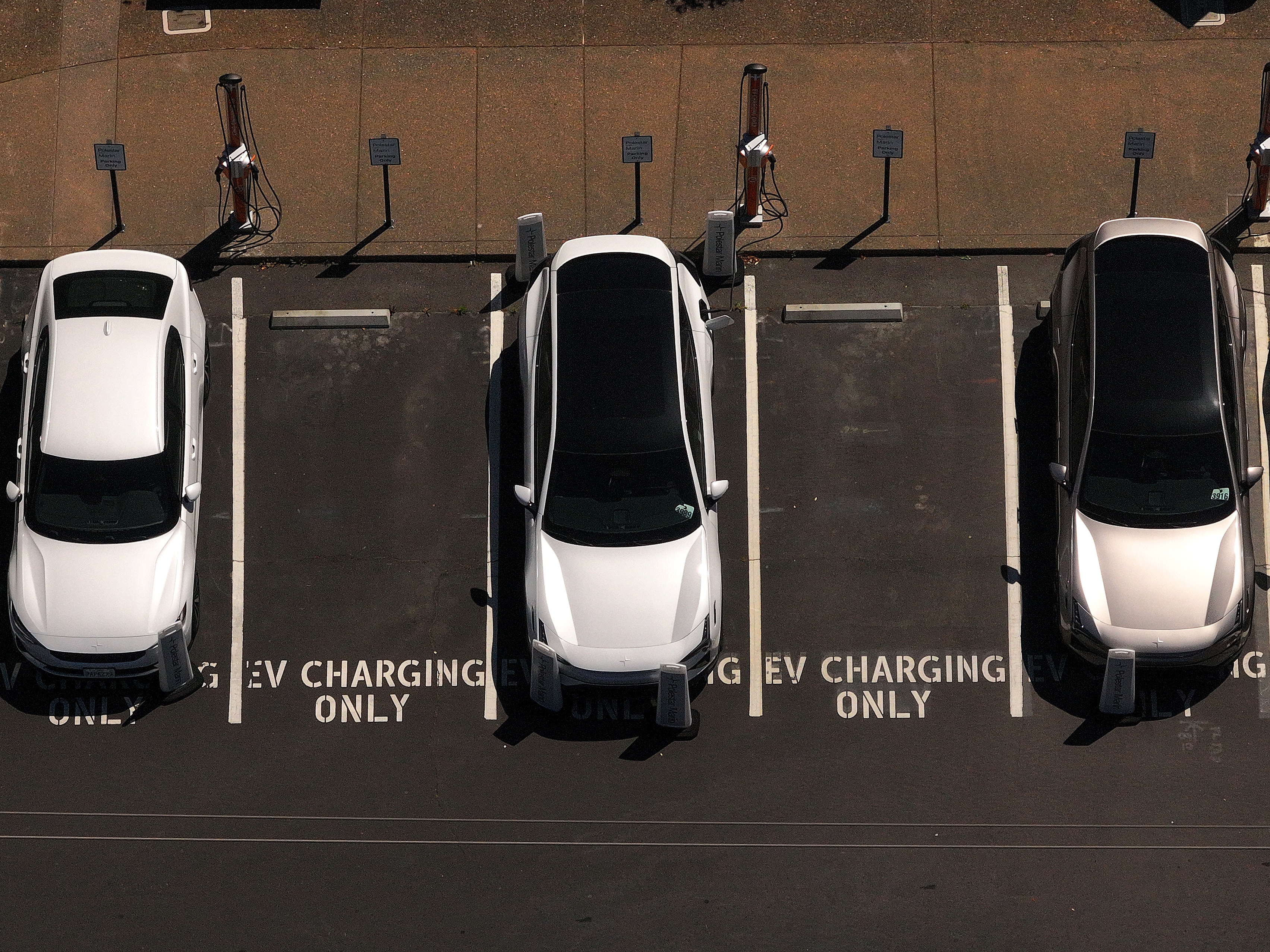 caption: Electric cars sit parked at a charging station  in Corte Madera, Calif., in May 2025.