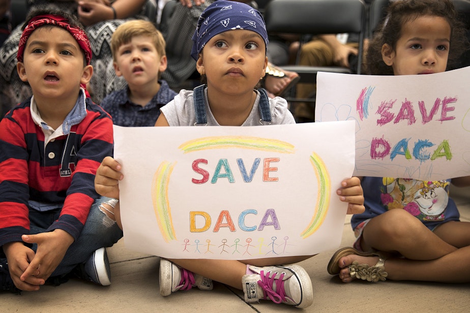 caption: Maya, center, a student at the Jose Marti Child Development Center holds a Save DACA sign during a community rally in support of DACA recipients on Tuesday, September 5, 2017, at El Centro De La Raza in Seattle. 