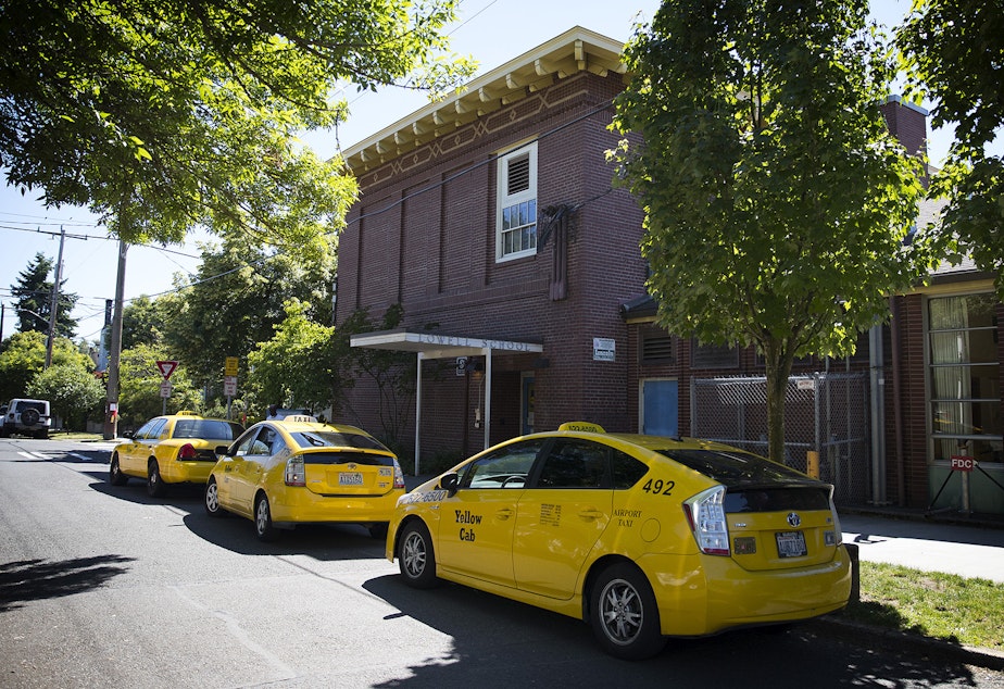caption: Taxis line up outside of Lowell Elementary on Friday to pick up students. The district is required to provide transportation for homeless students. That may mean taxis take them to and from shelters.