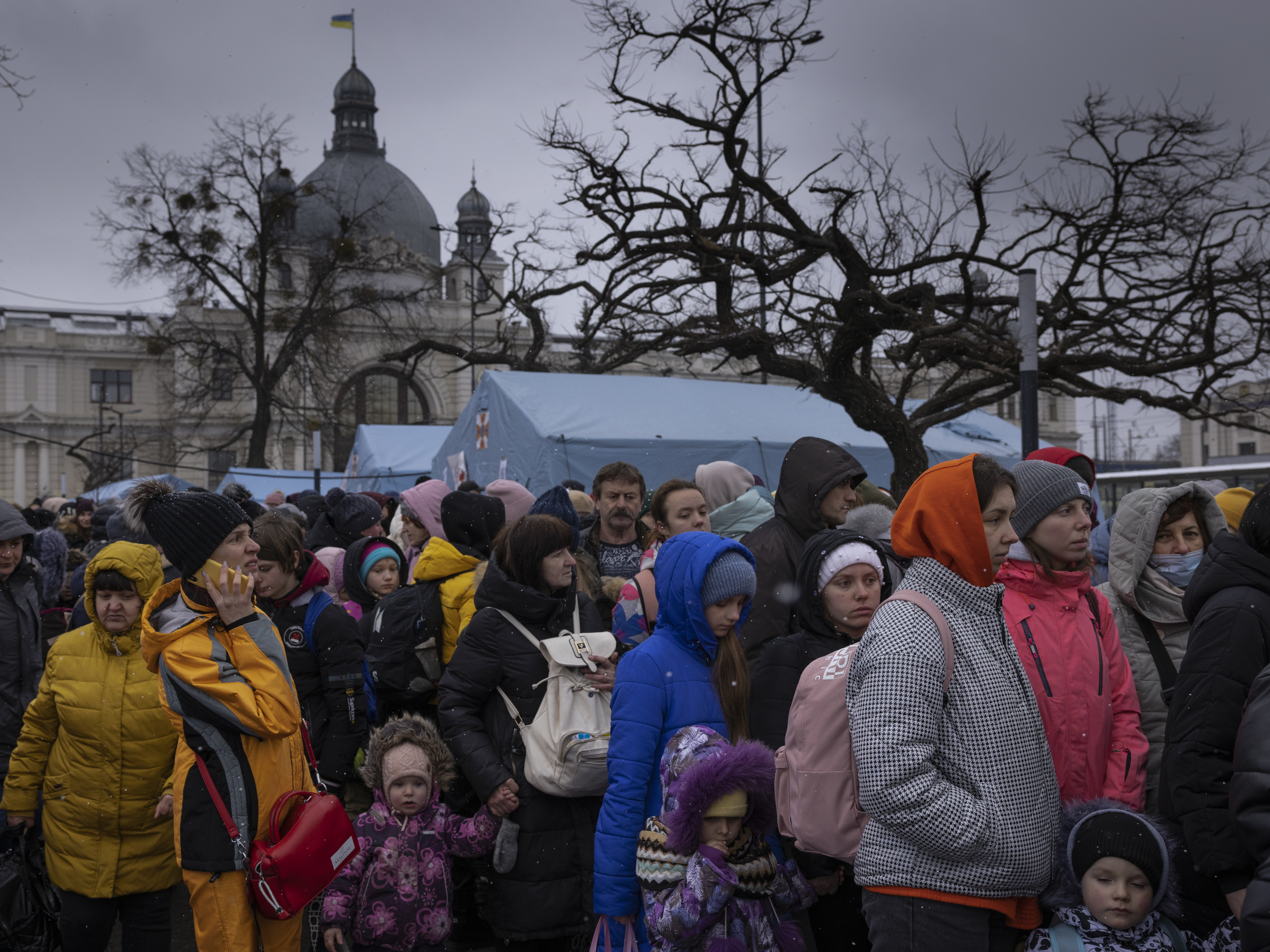 caption: Families wait to make their way from the main bus and train terminal on Saturday in Lviv, Ukraine. More than 1 million people have fled Ukraine following Russia's assault on the country, with many Ukrainians passing through Lviv on their way to Poland.