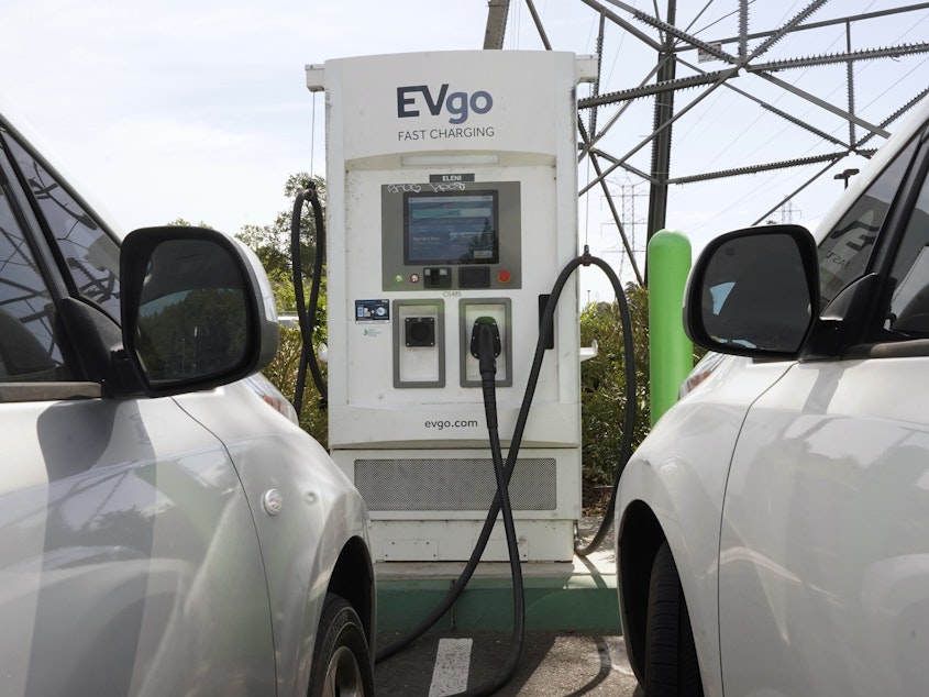 caption: Electric cars are parked at a charging station in Sacramento, Calif.