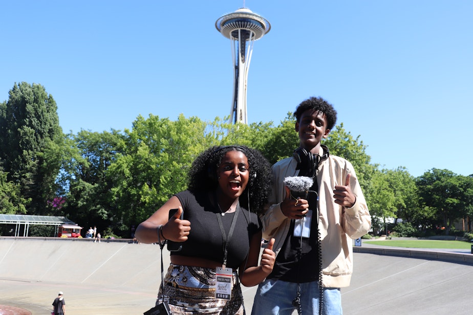 caption: Rediet Giday and Alex Mengisteab pose in front of the Space Needle while collecting interviews at Seattle Center on July 14, 2023.