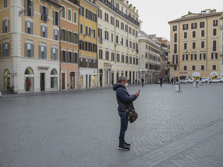 caption: A person wearing a face mask at the Piazza Di Spagna in Rome during the coronavirus emergency, on Tuesday, after the Italian government imposed national restrictions to control the spread of the COVID-19 disease.