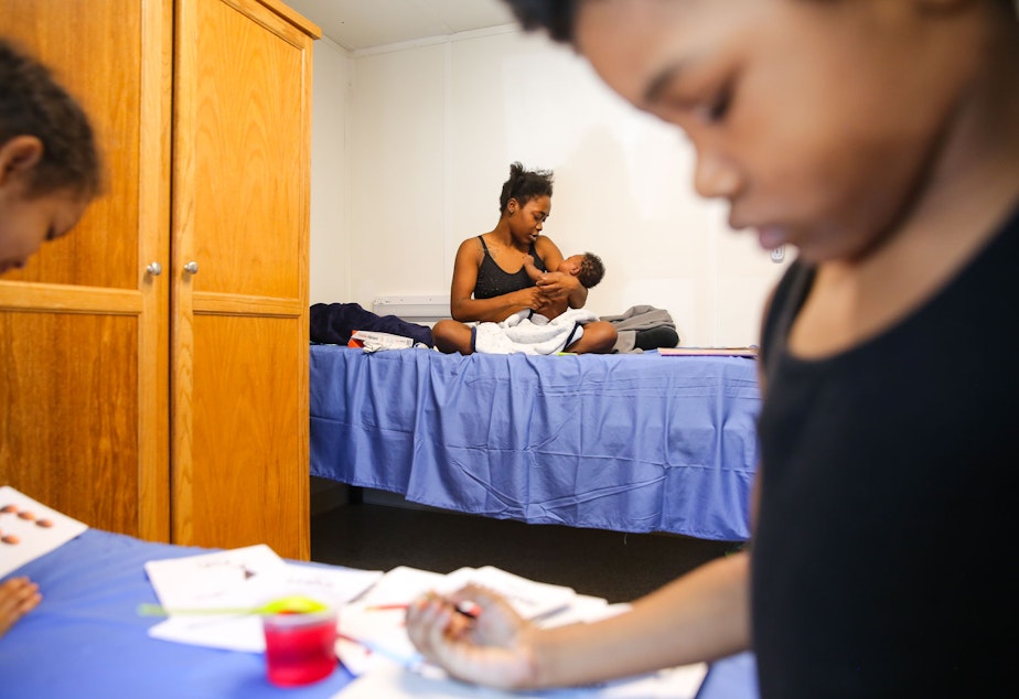 caption: Shadoria Wraggs holds her two-month-old son Gregory as her daughters Alycia, 8, left, and Av-ai, 5, look at flash cards inside their temporary room at the King County Cooling Center in White Center, Monday, June 28. The family, including father Gregory Wraggs Sr. and another daughter, has been living in their van for the past year and were able to stay in an air-conditioned unit at the cooling center as temperatures rose into the 100s.