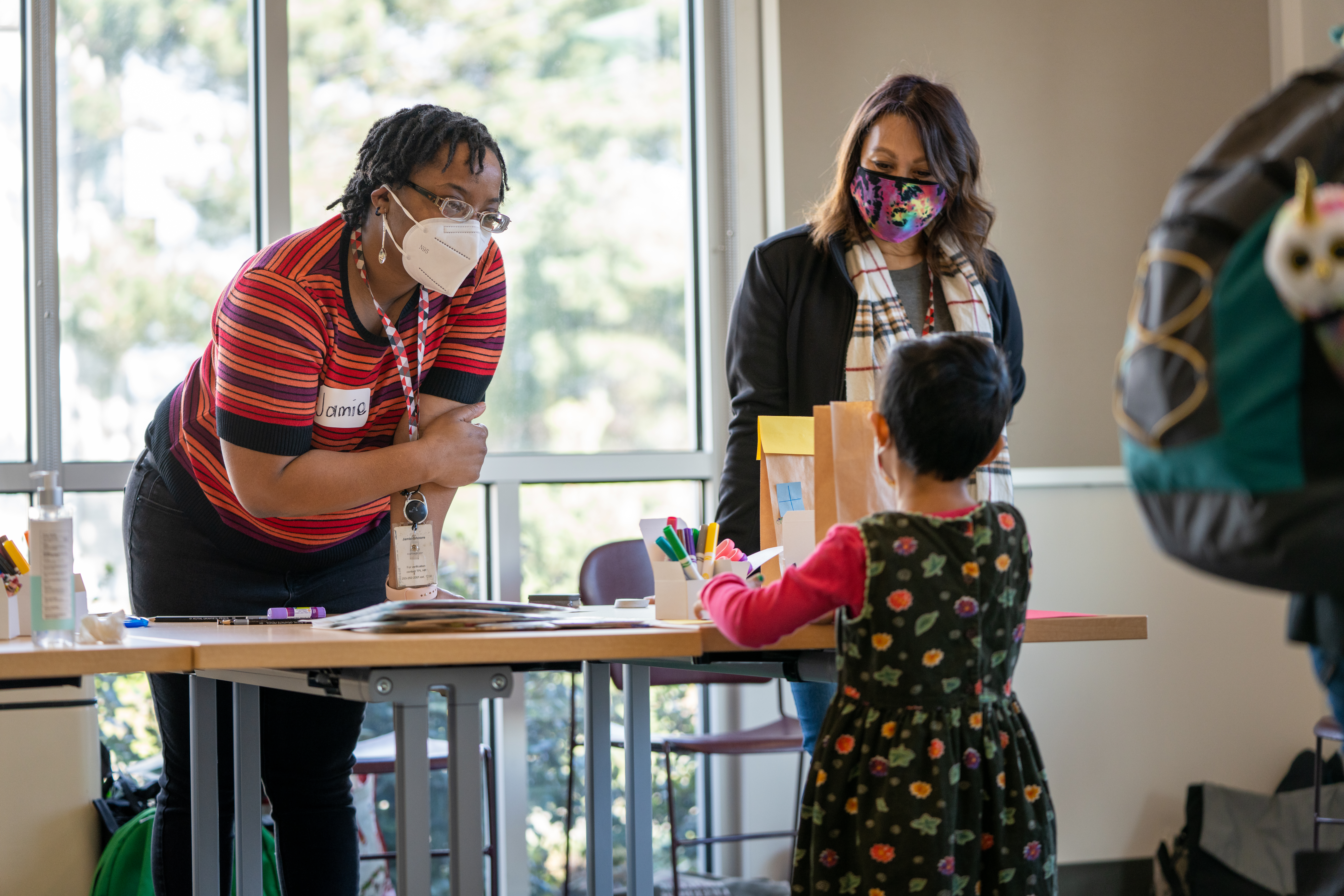 At the Library Visioning Workshop a library staff member shows a child how to do a craft activity