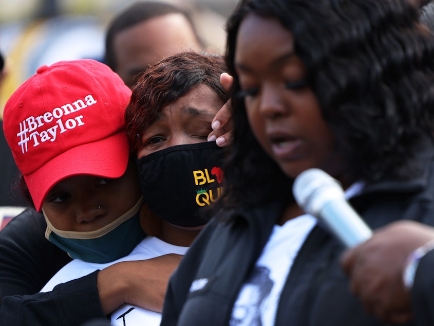 caption: "You didn't just rob me and my family, you robbed the world of a queen," Breonna Taylor's mother, Tamika Palmer, said in a statement read aloud Friday by Palmer's sister, Bianca Austin. In this photo, Ju'Niyah Palmer is seen wiping away tears from her mother's face.