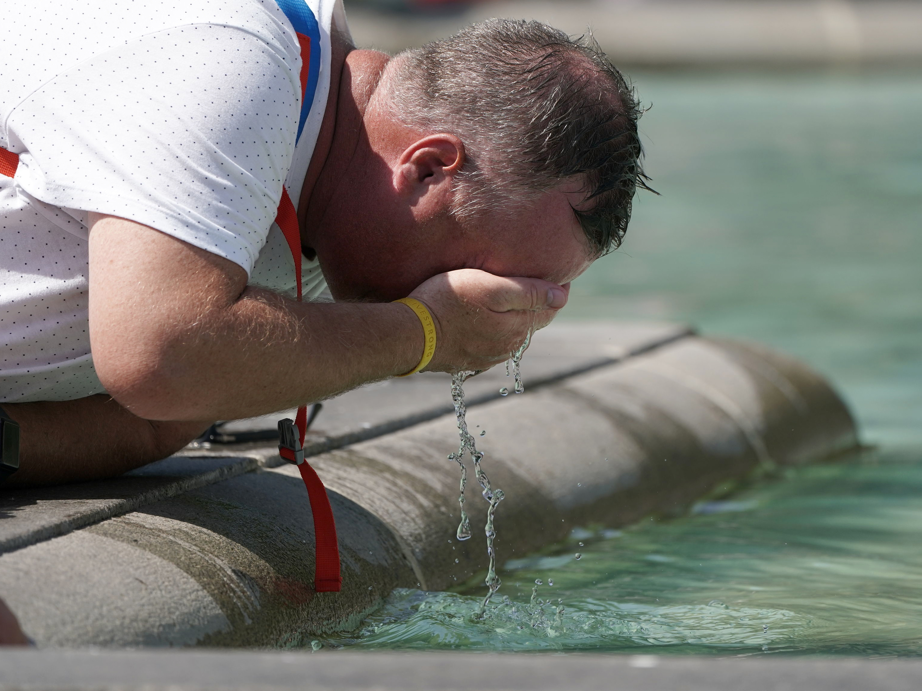 caption: A man refreshes his face at a fountain in Trafalgar Square in central London on Tuesday.