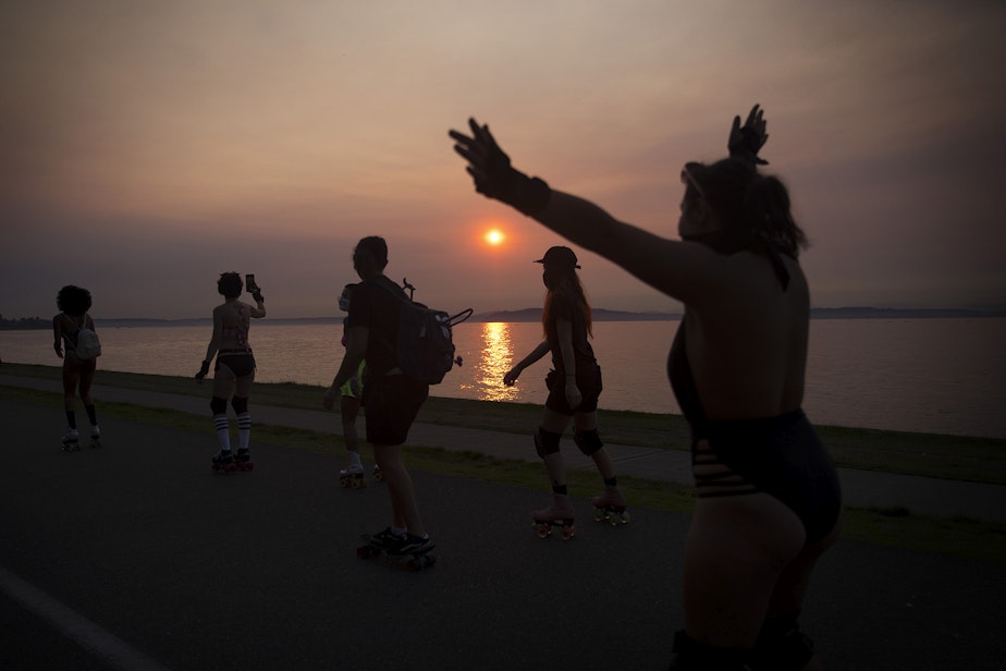 caption: Roller skaters skate along Alki Avenue Southwest during a Seattle Skates meet up as the sun sets on Wednesday, September 30, 2020, in Seattle.