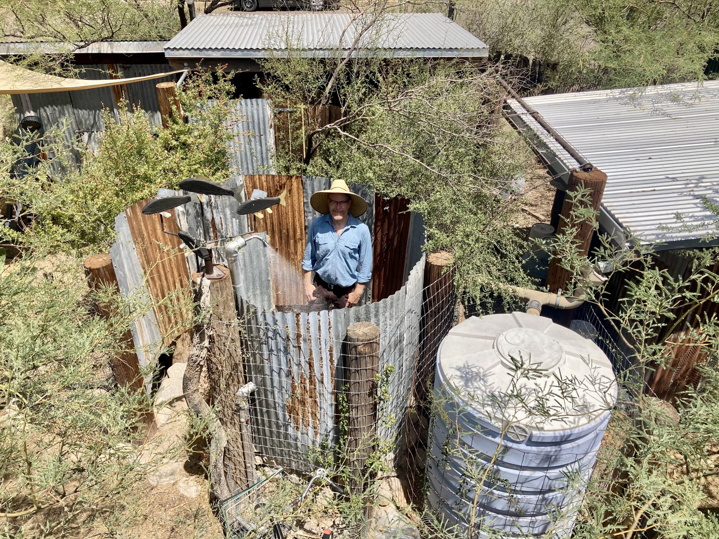 caption: Brad Lancaster in an outdoor shower that uses water collected from the rain. The Tucson resident has written a book about harvesting rainwater. (Peter O'Dowd/ Here & Now)
