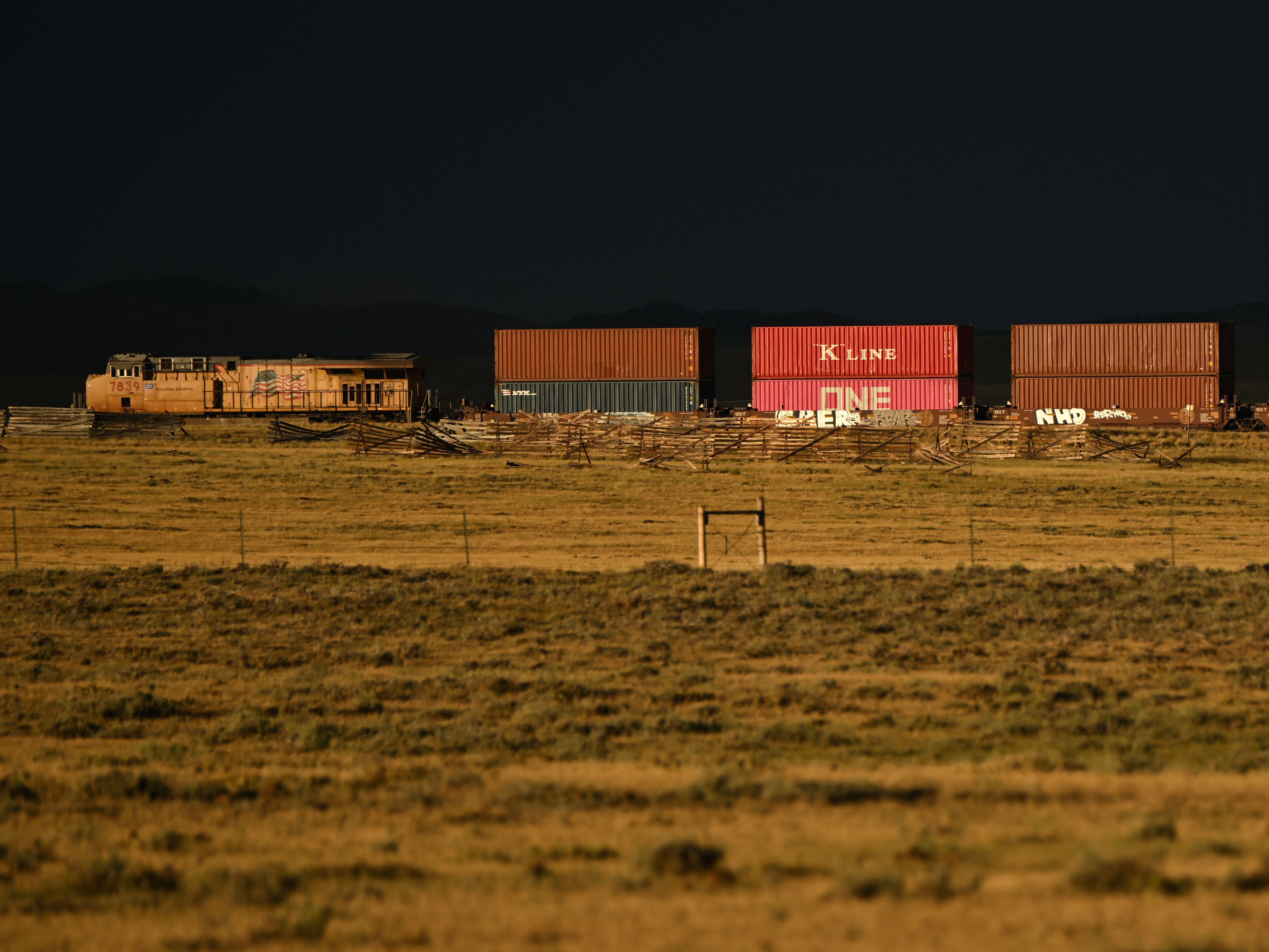 caption: A Union Pacific freight train carries cargo along a rail line at sunset in Bosler, Wyoming, on August 13, 2022.