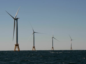 caption: Wind turbines, of the Block Island Wind Farm, tower over the water on October 14, 2016 off the shores of Block Island, Rhode Island.