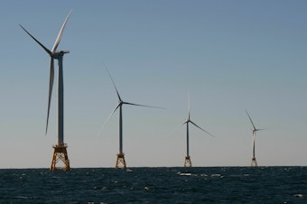 caption: Wind turbines, of the Block Island Wind Farm, tower over the water on October 14, 2016 off the shores of Block Island, Rhode Island.