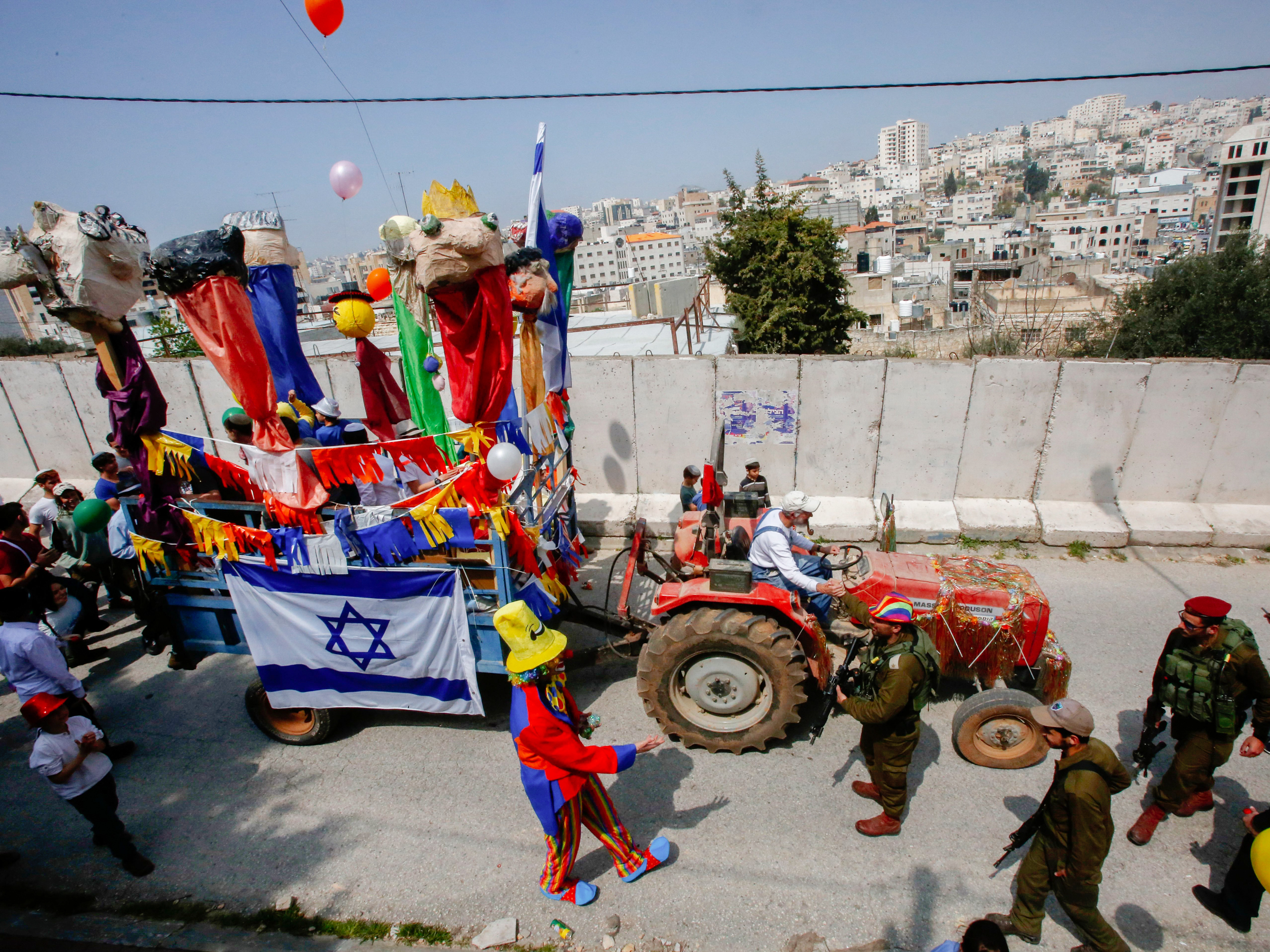 caption: Israeli settlers celebrate the Jewish Purim holiday at al-Shuhada street in the divided West Bank town of Hebron, on March 21.