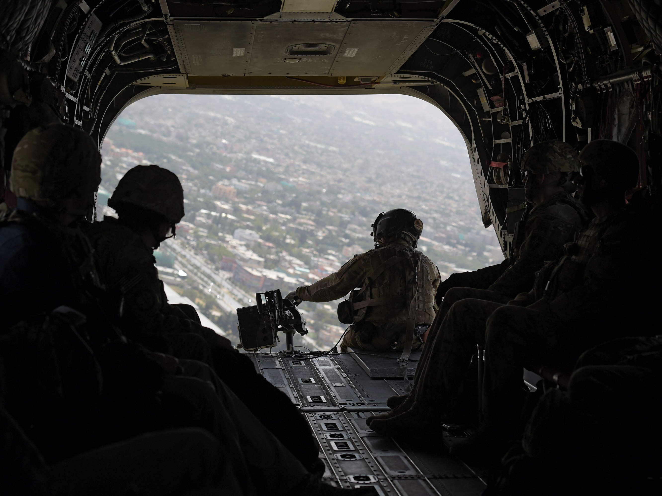 caption: In this photograph taken on Aug. 10, 2017, a U.S. soldier sits in the rear of Chinook helicopter while flying over Kabul.