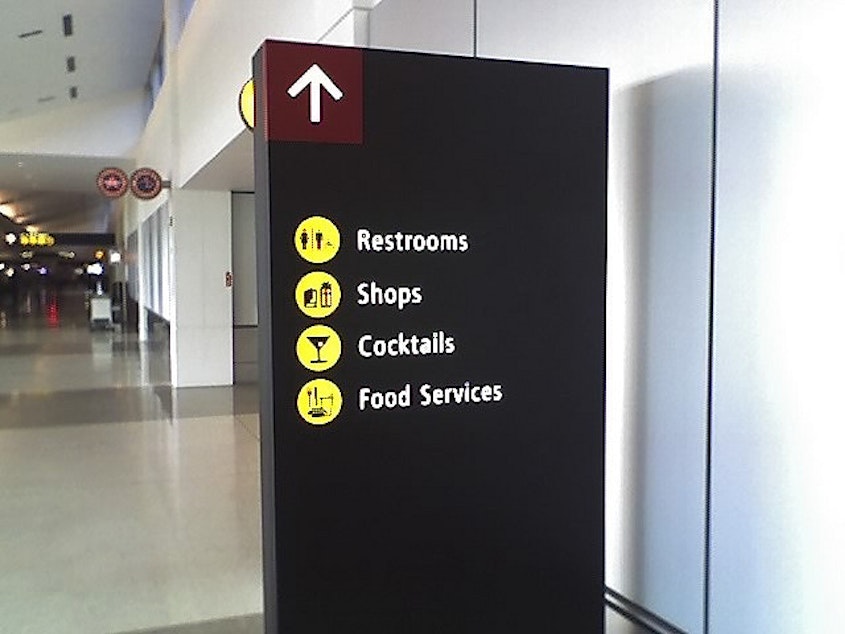 caption: Signage in SeaTac aiport points towards shopping and food areas: lightning rods in the minimum wage debate.