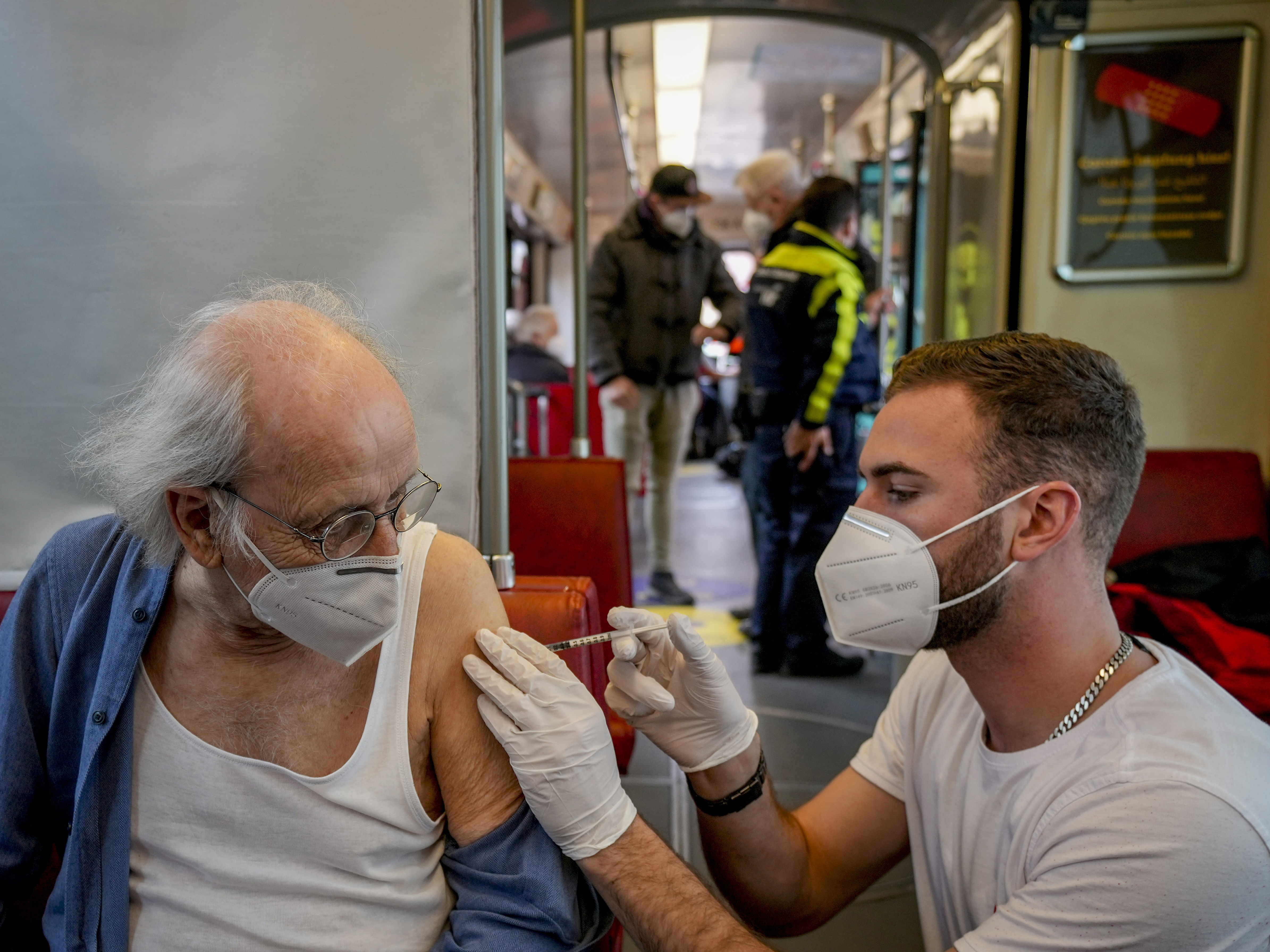 caption: An 85-year-old man receives a booster vaccination in the so-called "vaccination express" tram in central Frankfurt, on Nov. 4, 2021.