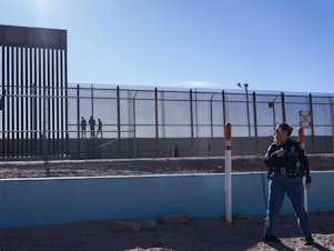 caption: A U.S. law enforcement officer stands guard by a fence along the U.S.-Mexico border at El Paso, Texas.