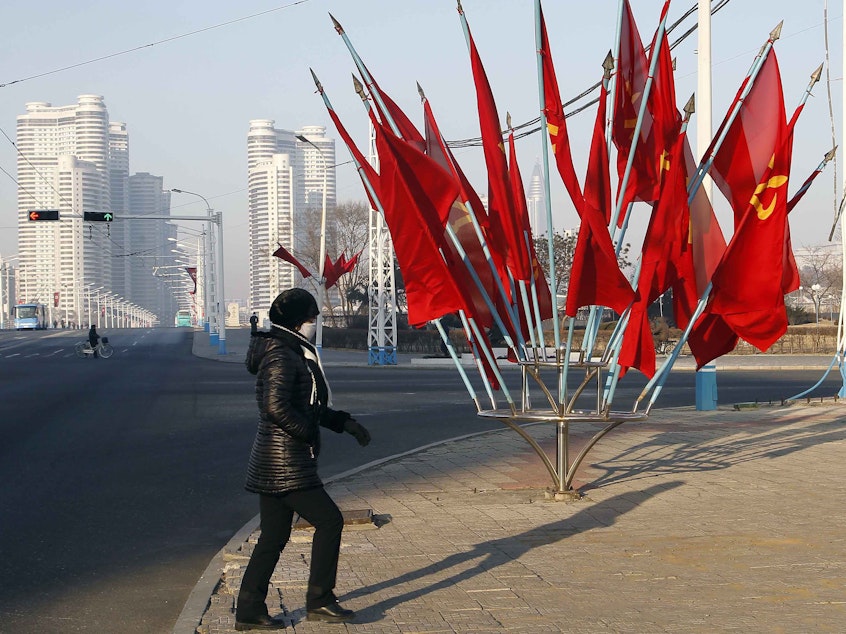 caption: A person passes by a bouquet of Workers Party flags along a main street of the Central District in Pyongyang, North Korea, last week.